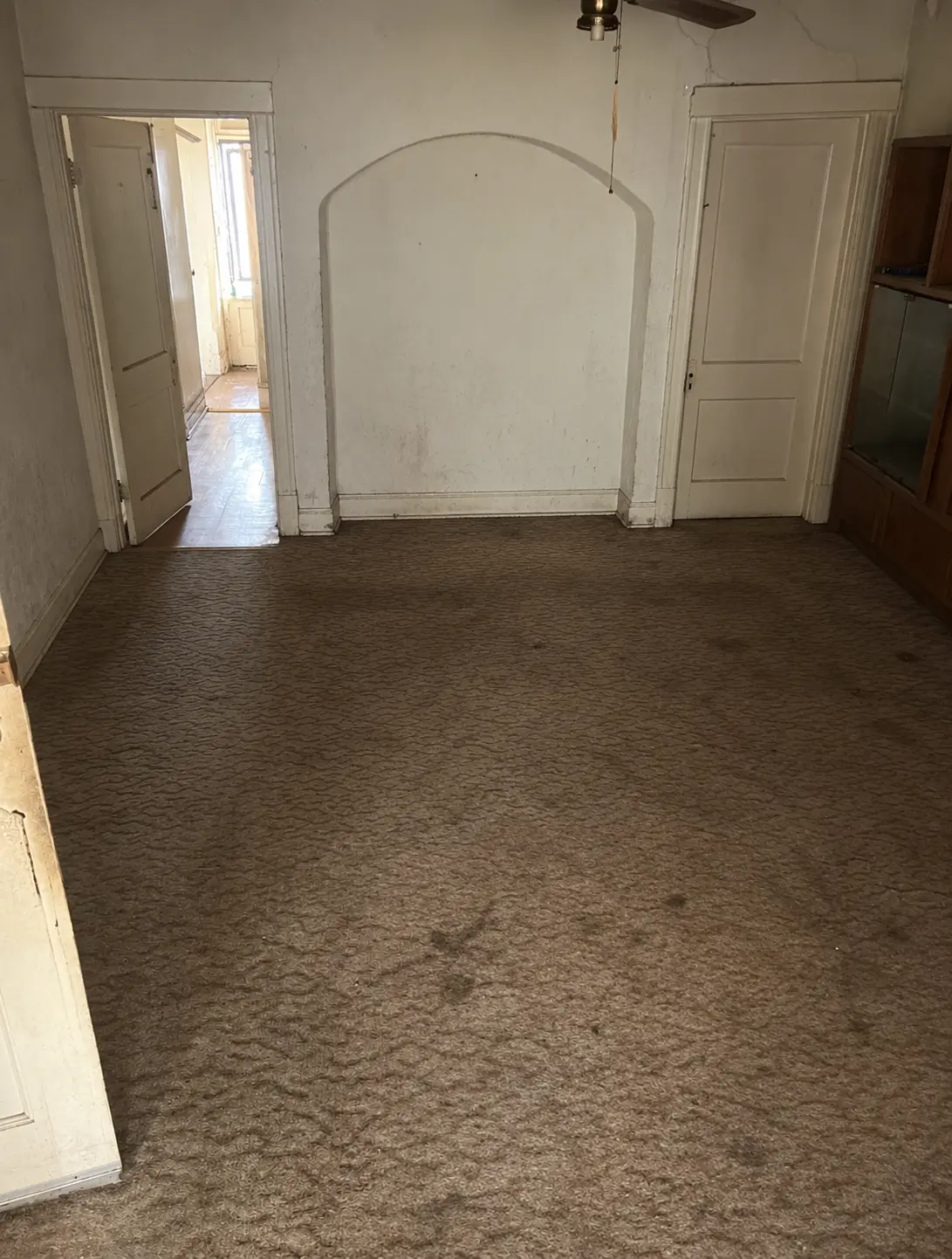 The same room fully emptied with bare carpet after the cleanout