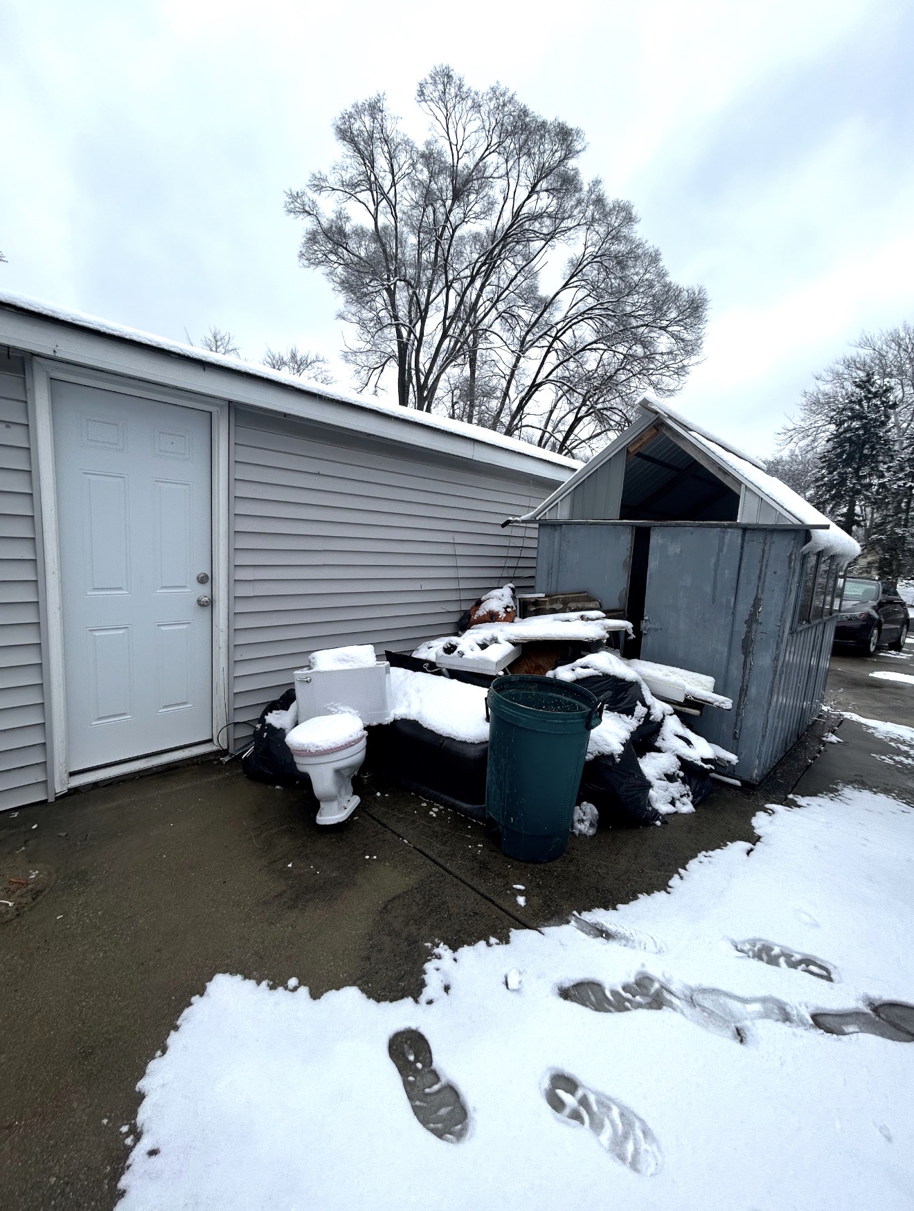 Driveway and garage area piled with junk and bulk items before removal