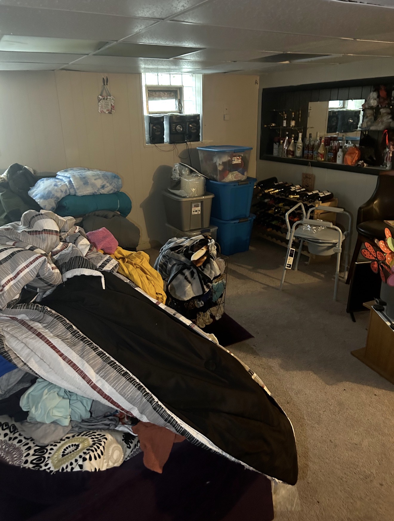 Basement filled with clothing, bedding, bins and household items before a full cleanout