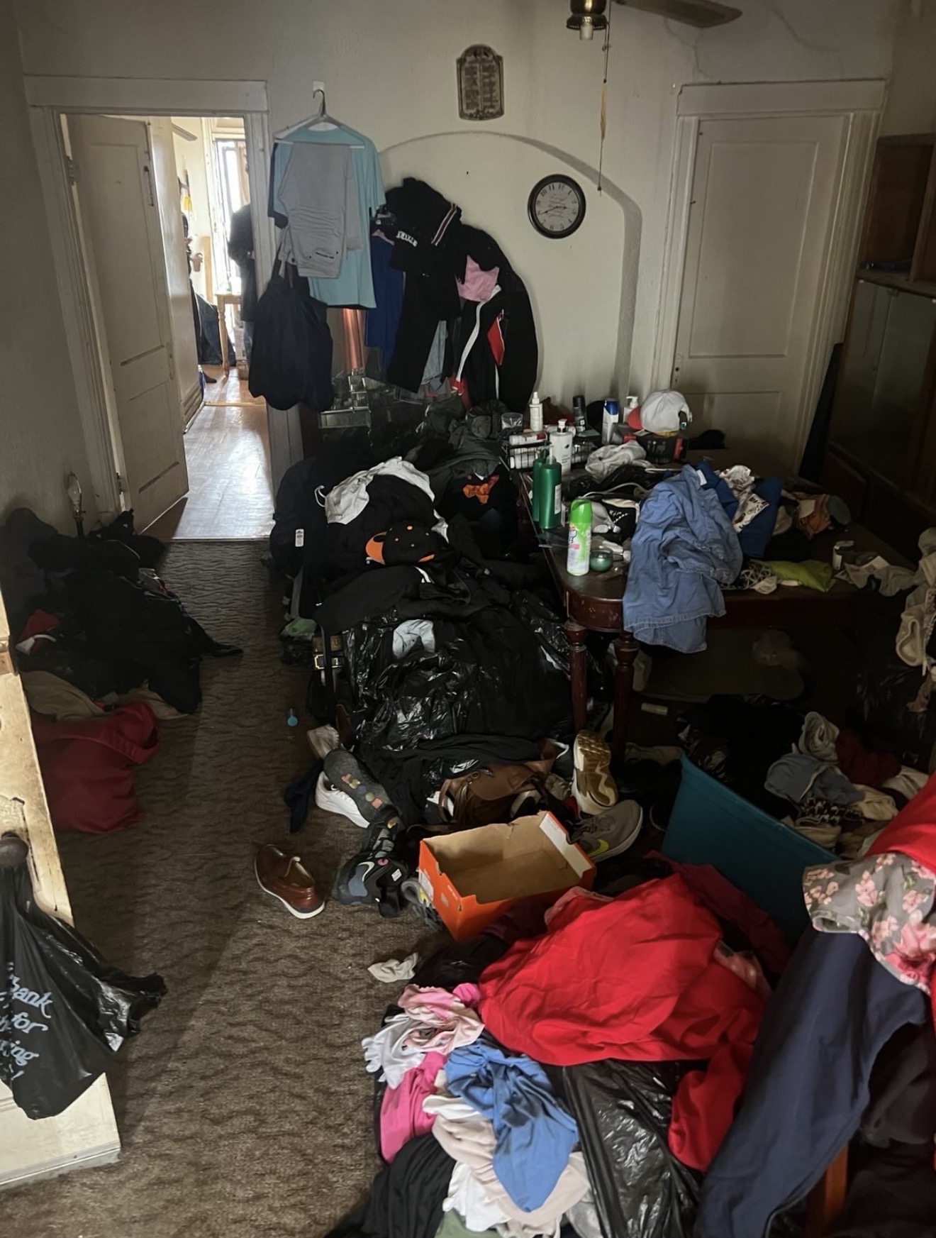 Room piled with clothing, bags and household items before a full contents cleanout